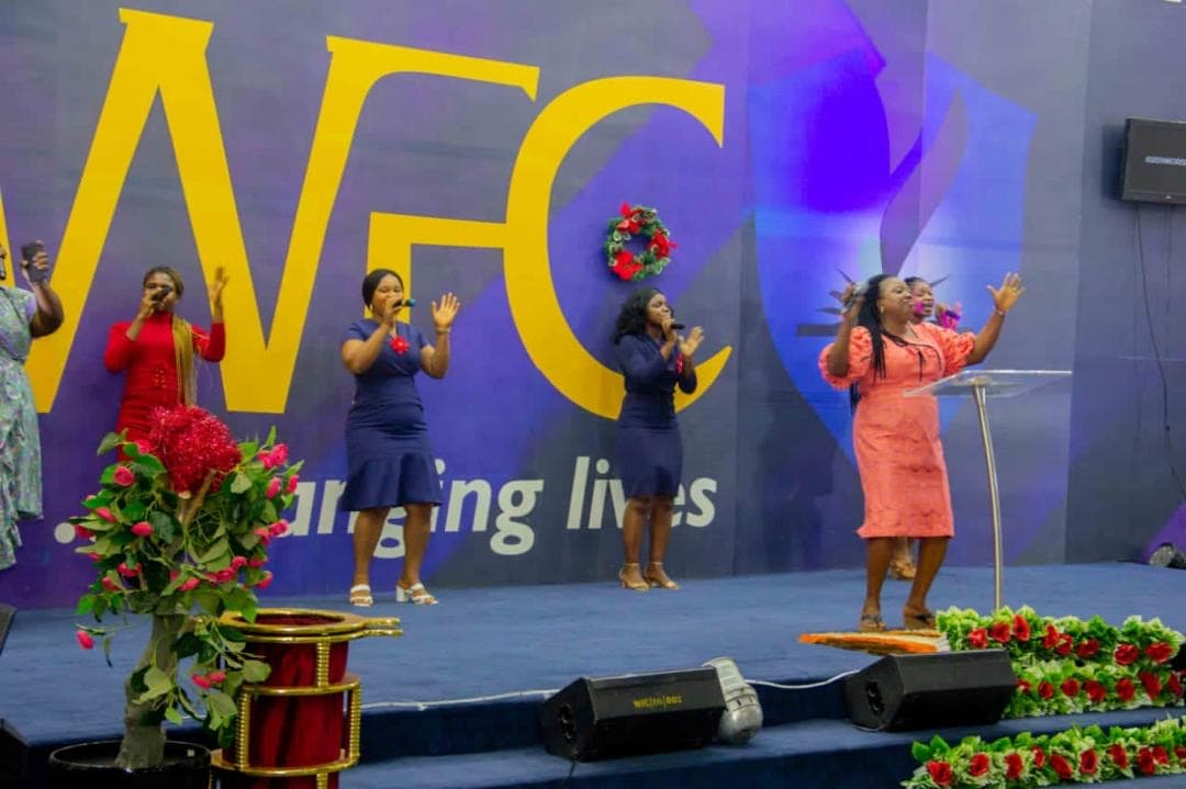 Praise team singing in red and coral outfits on stage